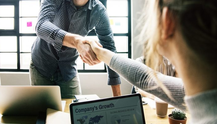 Handshake with a computer in the background.